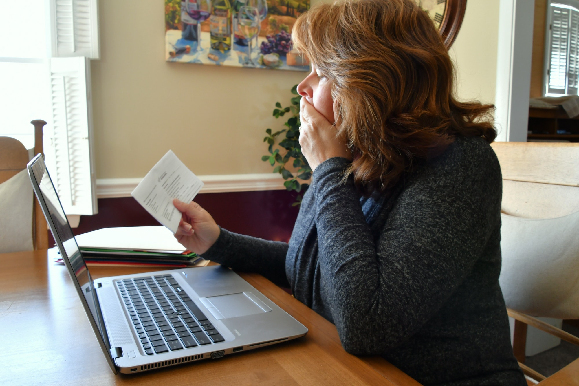 Serious female using laptop looking a invoice statement while paying bills online or filing taxes