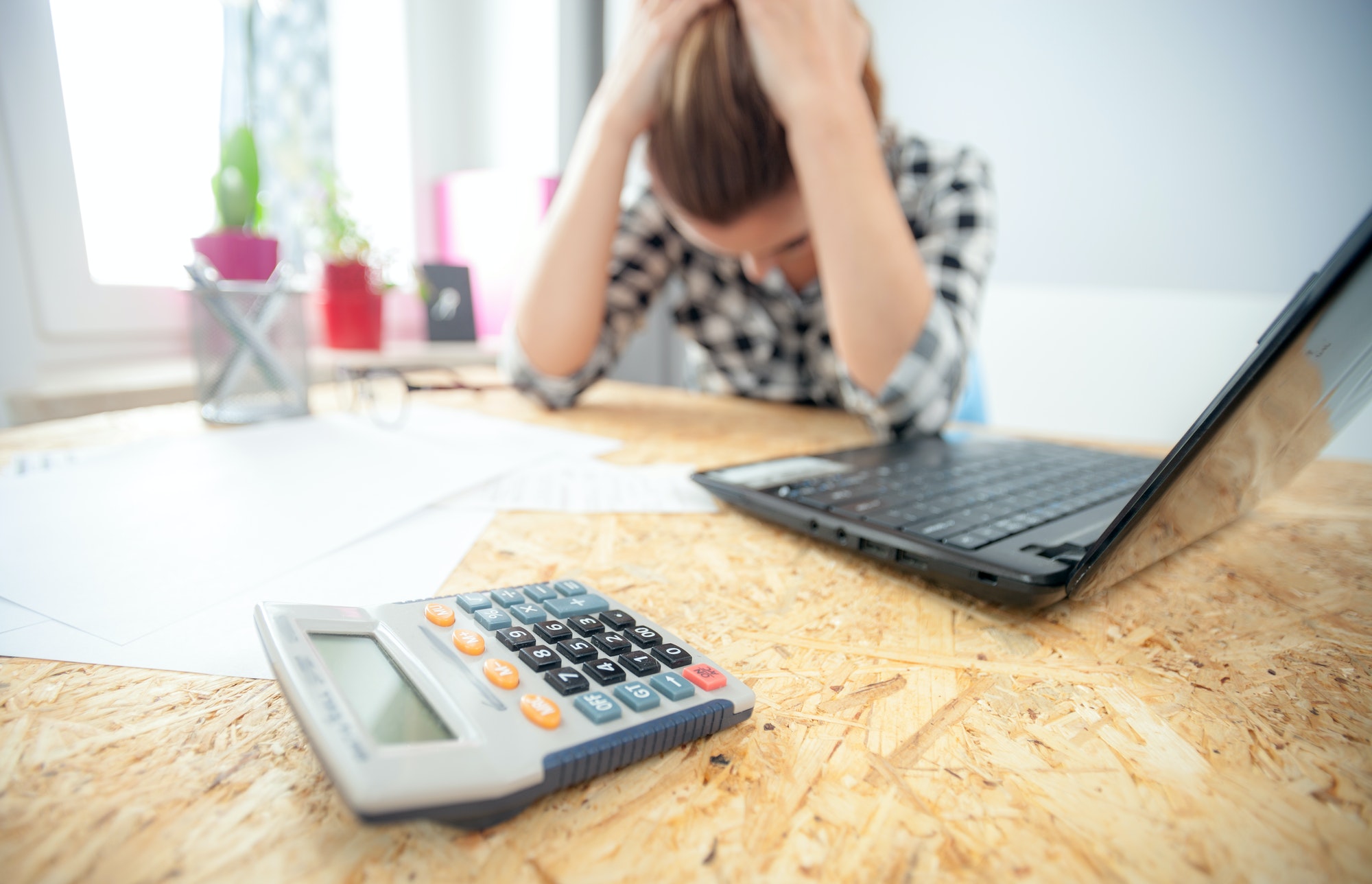 Stressed and depressed woman in home office calculating bills